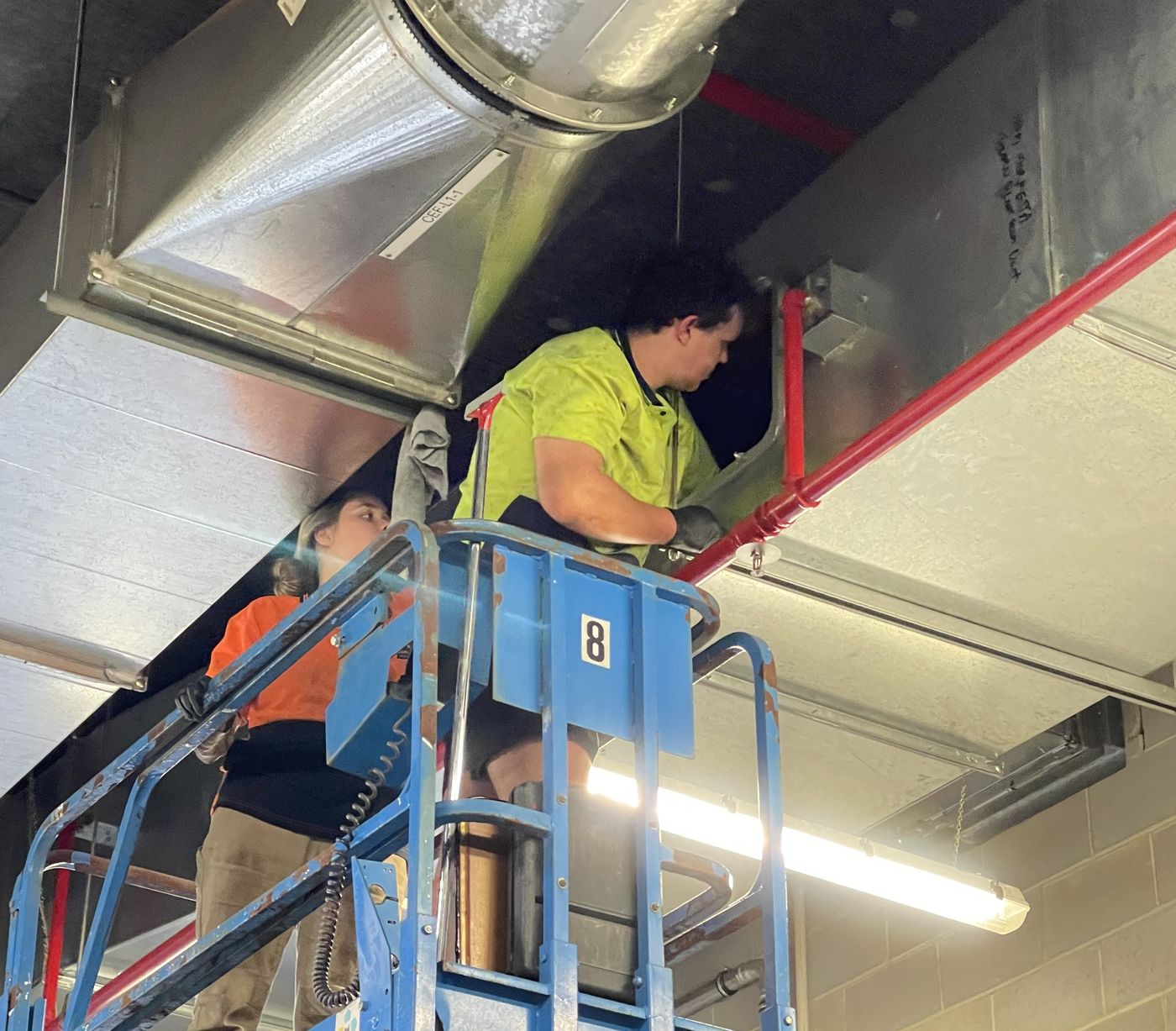 Cadin team cleaning commercial exhaust ductwork from a scissor lift